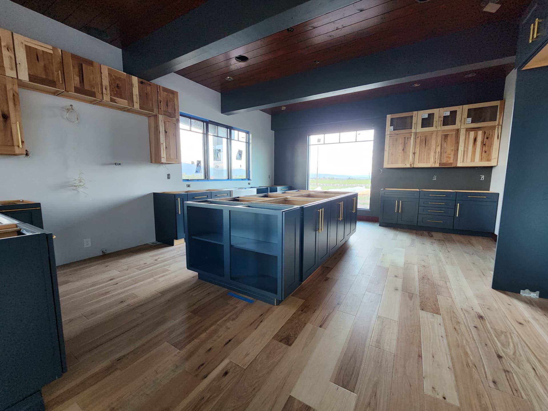 Kitchen with navy island cabinets, natural wood upper cabinets, and dark wood ceiling
